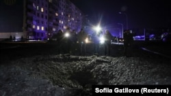 Люди стоять біля вирви, що з'явилася після удару російського безпілотника в Харкові, 30 січня 2024 року
