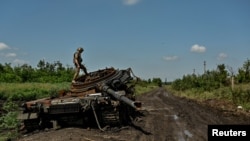 Український військовослужбовець оглядає знищений російський танк у селі Новодарівка Запорізької області, 21 липня 2023 року