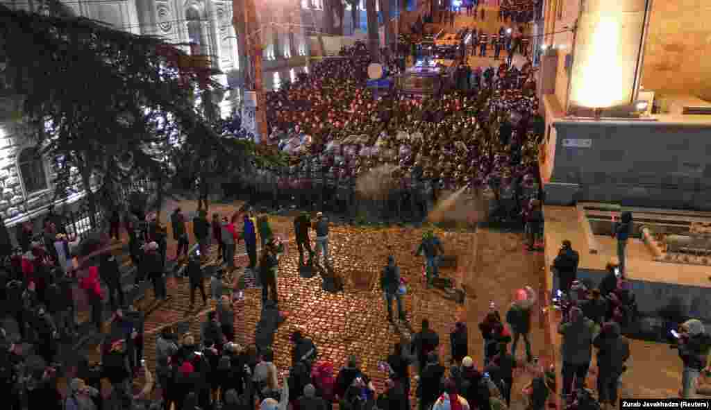 Поліцейські витісняють протестувальників з вулиці, яка веде до заднього входу в будівлю парламенту Грузії (на фото праворуч)