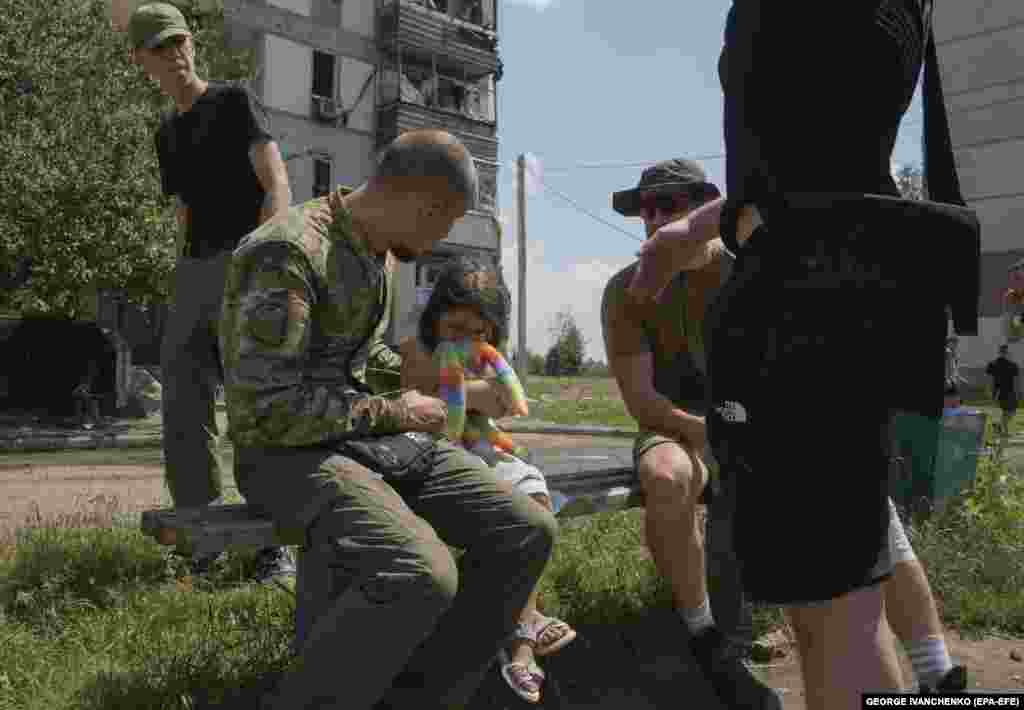Чоловіки заспокоюють дівчинку, яка плаче після російського ракетного удару по житловій забудові у Первомайському. 4 липня 2023 року 