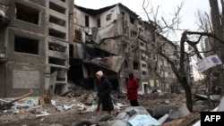 Місцеві жителі йдуть повз зруйнований російським ракетним обстрілом житловий будинок у місті Селидове Донецької області, 16 лютого 2024 року