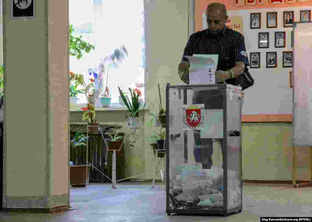 Дауыс беру жәшігіне бюллетень салып жатқан Қырым тұрғыны. 