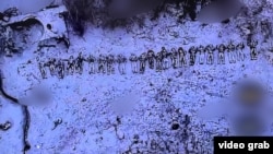Видно несколько десятков тел на фоне разбитой техники