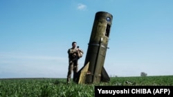 Український військовий оглядає розгінну ступінь російської балістичної ракети, яка впала в полі на Харківщині, 25 квітня 2022 року
