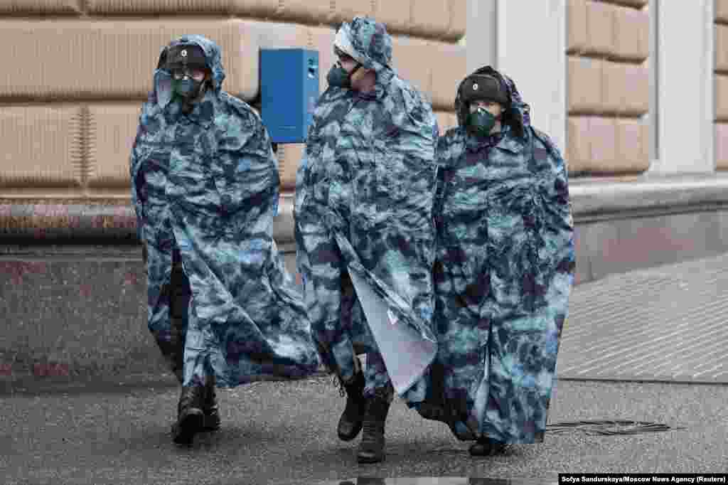 Расейскія праваахоўнікі ў плашчах і ахоўных масках патрулююць вуліцы ў Маскве падчас пандэміі. 