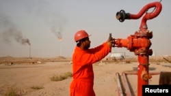 Нефтяник на трубопроводе близ нефтеперерабатывающего завода в иракском городе Ан-Наджафе.